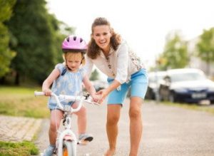 Mother-helping-her-little-girl-learn-to-ride-a-bike-e1457460085747