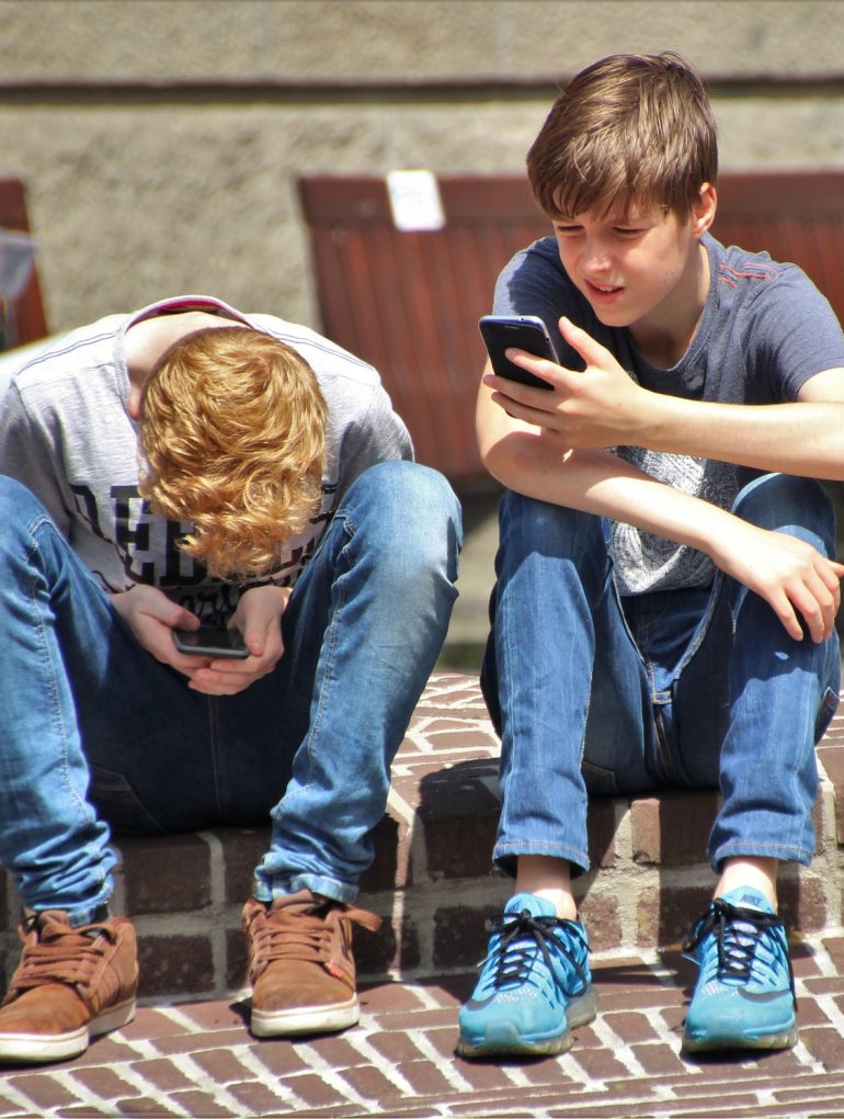 Two boys looking at cell phones