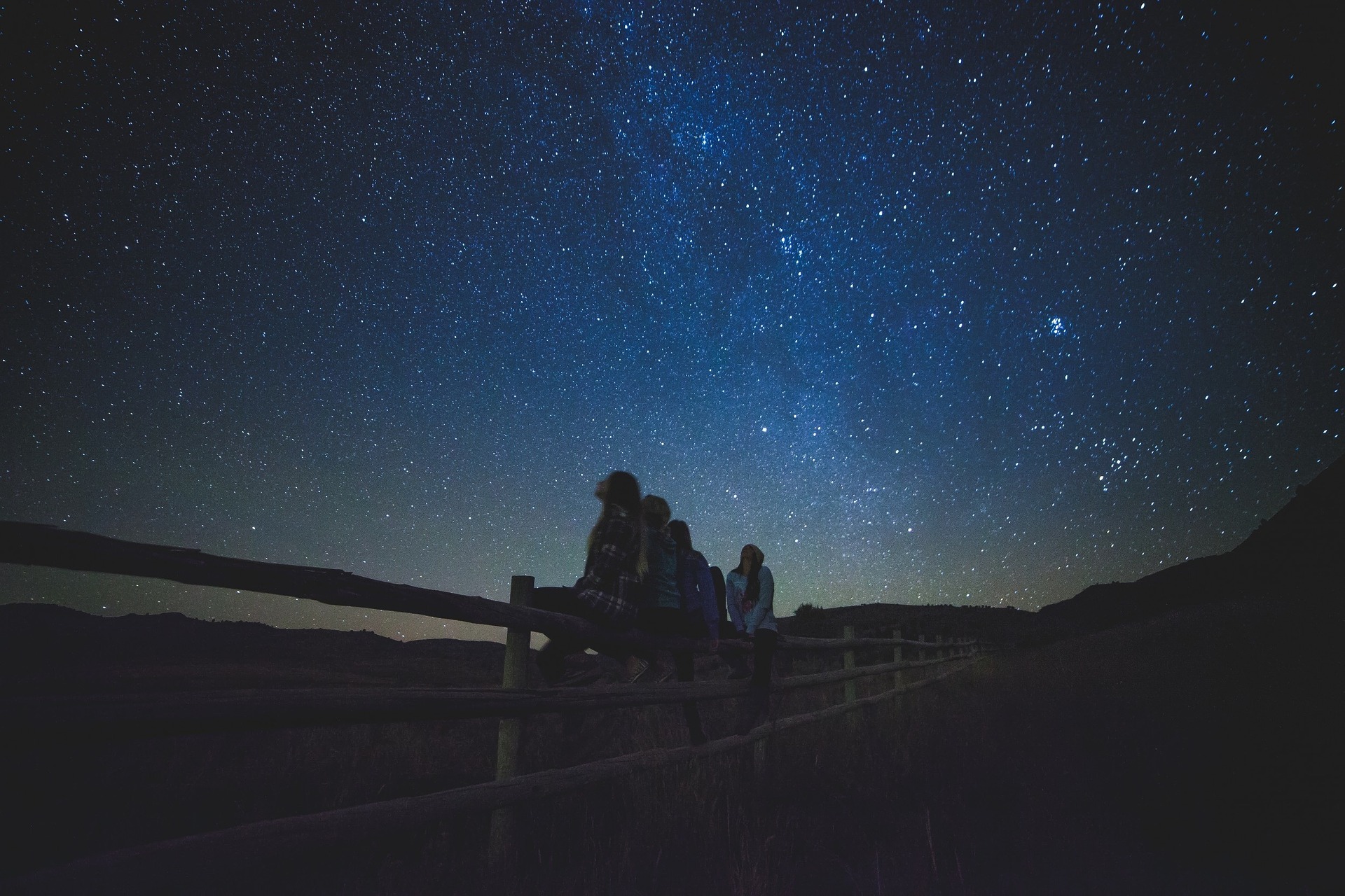 People sitting on a fence watching stars