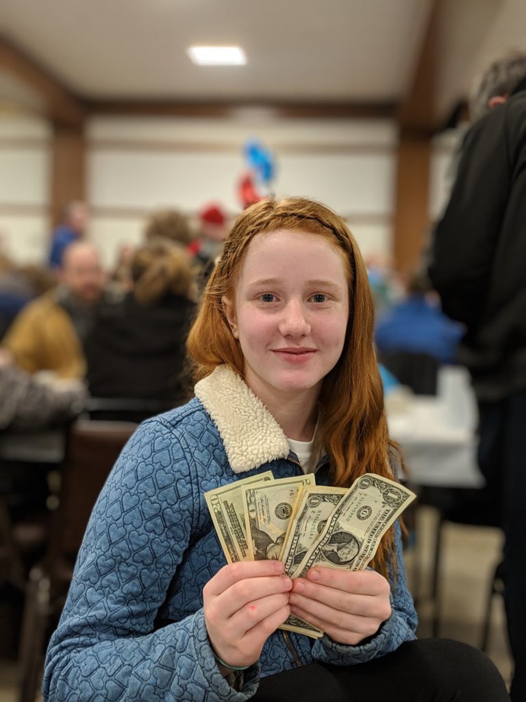 Happy young woman holding bills in a fan shape.