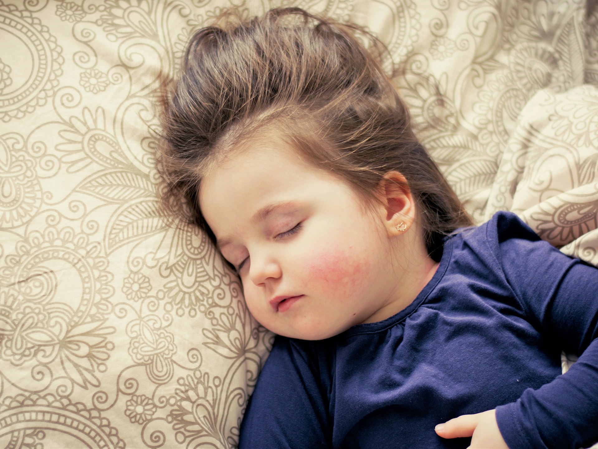 Toddler sleeping on tan pillow with paisley pattern
